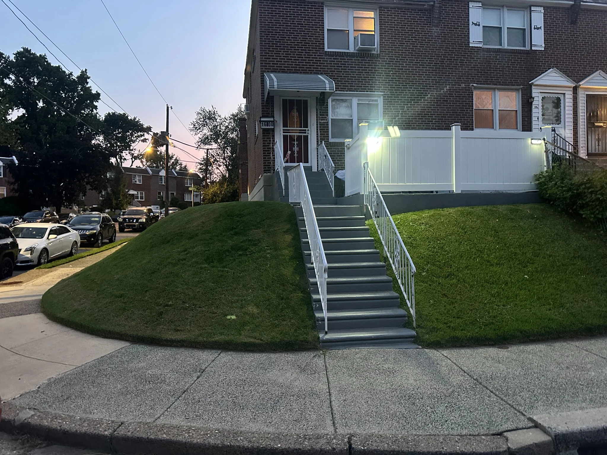 Freshly maintained sloped front lawns beside a residential stairway and sidewalk in a Delaware County neighborhood