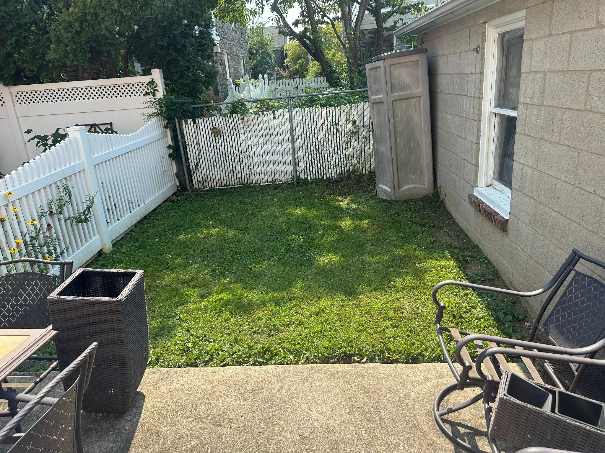 Small fenced backyard with freshly maintained grass beside a patio and residential garage